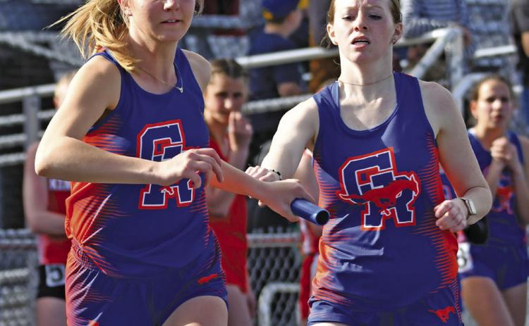 Photo by Melissa Grover Junior Rylie Barker hands off to teammate senior Natalie Popken during the 4x800 meter relay. The relay team would earn a second place medal in the event with a time of 11:09.05.
